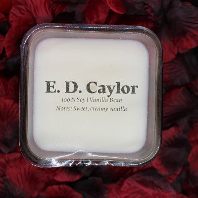 E. D. Caylor vanilla bean soy candle with lid on it sitting on a bed of rose petals
